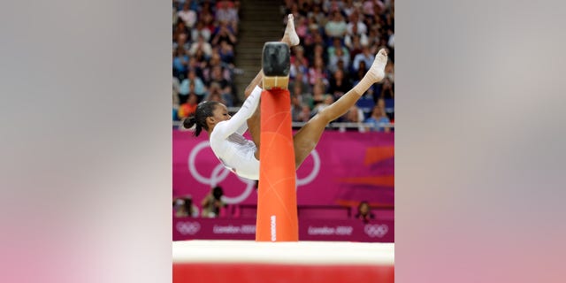 U.S. gymnast Gabrielle Douglas loses her balance and hangs onto the balance beam during the artistic gymnastics women's apparatus finals at the 2012 Summer Olympics, Tuesday, Aug. 7, 2012, in London. (AP Photo/Gregory Bull)