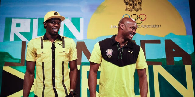 Jamaican sprinters Usain Bolt, left, and Asafa Powell, right, joke as they pose for photographers at the end of a press conference by the Jamaica Olympic Association ahead of the 2012 Summer Olympics, Thursday, July 26, 2012, in London. The opening ceremonies for the 2012 London Olympics will be held Friday, July 27. (AP Photo/Ben Curtis)