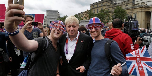 London Mayor Boris Johnson, center, poses for pictures with Britain team fans, following a photo-op with London ambassadors, the volunteers working around the city to give tourists directions and information, in central London, Tuesday, July 31, 2012. Johnson said he doesnt have eyes for top Britains leadership post - despite the unprecedented forum hes now enjoying during the Summer Olympics. (AP Photo/Lefteris Pitarakis)
