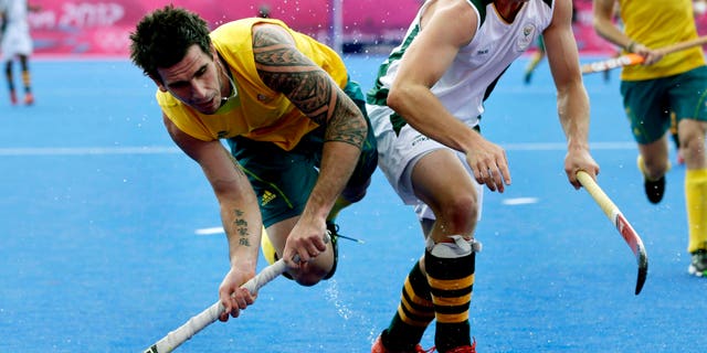 Australia's Kieran Govers, left, shoots towards the goal as South Africa's Andrew Cronje defends during a men's field hockey preliminary match at the 2012 Summer Olympics, Monday, July 30, 2012, in London. (AP Photo/Bullit Marquez)