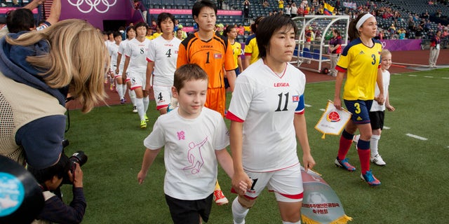 July 25, 2012: The North Korean, center, and Colombian women's soccer team walk out on to the field before their group B match, prior to the start of the London 2012 Summer Olympics at Hampden Park Stadium in Glasgow.