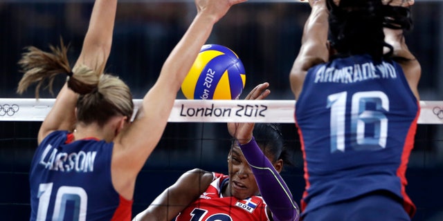 Aug. 7, 2012: United States' Jordan Larson, left, and Foluke Akinradewo, right, block a spike from Dominican Republic's Bethania de la Cruz de Pena during a women's quarterfinal volleyball match at the 2012 Summer Olympics in London.
