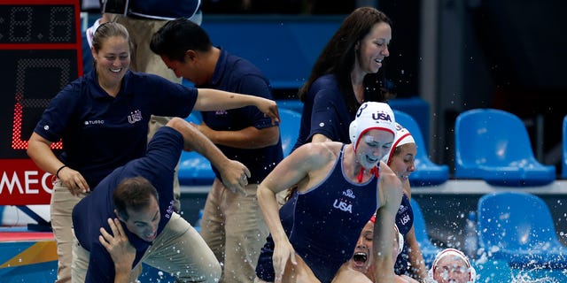United States coach Adam Krikorian, left, is pulled into the pool moments after the team beat Spain during the gold medal women's water polo match at the 2012 Summer Olympics, Thursday, Aug. 9, 2012, in London. (AP Photo/Julio Cortez)