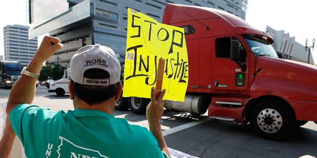 LOS ANGELES, CA - NOVEMBER 13:  A truck drives near City Hall to protest shipping container fees being assessed against independent truckers as part of the ports' Clean Truck Program to allow only newer, less-polluting trucks at the ports, on November 13, 2009 in Los Angeles, California. The members of the National Port Drivers Association, who work the ports of Los Angeles and Long Beach,  formed caravans from the ports to City Hall in downtown Los Angeles to demonstrate against the fees that they say impact their wages and hours. In October, the Port of Long Beach and the American Trucking Assn. reached a settlement over disputed elements of the air pollution cleanup plan. The port drop requirements not directly related to cleaning up the environment such as a demand for trucking companies to file financial reports, and truckers agreed to emissions, safety and security requirements. In an effort to get rid of dirty trucks, the ban on all 1988 and older trucks from the ports remains and as of January, only 2004-or-later trucks will be allowed in the port complex. Thousands of trucks make daily trips into and out of the ports of Long Beach and Los Angeles which make up the busiest seaport complex in the nation.  (Photo by David McNew/Getty Images)