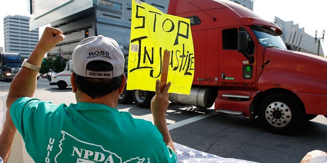 LOS ANGELES, CA - NOVEMBER 13: A truck drives near City Hall to protest shipping container fees being assessed against independent truckers as part of the ports' Clean Truck Program to allow only newer, less-polluting trucks at the ports, on November 13, 2009 in Los Angeles, California. The members of the National Port Drivers Association, who work the ports of Los Angeles and Long Beach, formed caravans from the ports to City Hall in downtown Los Angeles to demonstrate against the fees that they say impact their wages and hours. In October, the Port of Long Beach and the American Trucking Assn. reached a settlement over disputed elements of the air pollution cleanup plan. The port drop requirements not directly related to cleaning up the environment such as a demand for trucking companies to file financial reports, and truckers agreed to emissions, safety and security requirements. In an effort to get rid of dirty trucks, the ban on all 1988 and older trucks from the ports remains and as of January, only 2004-or-later trucks will be allowed in the port complex. Thousands of trucks make daily trips into and out of the ports of Long Beach and Los Angeles which make up the busiest seaport complex in the nation. (Photo by David McNew/Getty Images)
