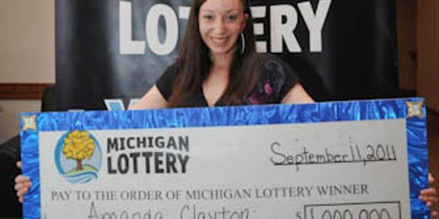 March 8: Photo provided by the Michigan Lottery, Amanda Clayton holds her $1 million lottery check. Clayton, who continued to get food stamps after winning a $1 million lottery jackpot, has been charged with welfare fraud.