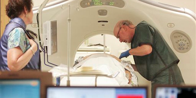 FILE - In this June 3, 2010, file photo, Dr. Steven Birnbaum works with a patient in a CT scanner at Southern New Hampshire Medical Center in Nashua, N.H. A national study suggests the world's top cancer killer isn't always as deadly as doctors once thought, finding that more than 18 percent of lung cancers detected in screening scans are likely so slow growing that theyâd never cause problems. But the provocative results are unlikely to change how doctors treat lung cancer. (AP Photo/Jim Cole, File)