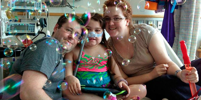 FILE - In this May 30, 2013 file photo provided by the Murnaghan family, Sarah Murnaghan, center, celebrates the 100th day of her stay in Children's Hospital of Philadelphia with her father, Fran, left, and mother, Janet. The 10-year-old suburban Philadelphia girl received a lung transplant there Wednesday, June 12, 2013, her family said. (AP Photo/Murnaghan Family, File)