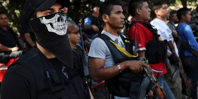 Men belonging to the Self-Defense Council of Michoacan, (CAM), stand at attention during the burial of Mario Perez at a cemetery in Antunez, Mexico, Wednesday, Jan. 15, 2014. Perez was one of the three civilians killed a day earlier by federal forces after they tried to disarm men belonging to a self-defense group that is fighting to rid the Knights Templar drug cartel in a region of Michoacan state known as Tierra Caliente. (AP Photo/Felix Marquez)