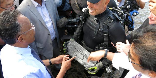In this photo taken Thursday, May, 7, 2015 underwater explorer Barry Clifford, right, presents a silver bar he believes is part of the treasure of the pirate Captain Kidd, to the president of Madagascar, Hery Rajaonarimampianina, left, on Sainte Marie Island, Madagascar. (AP Photo/Martin Vogl)