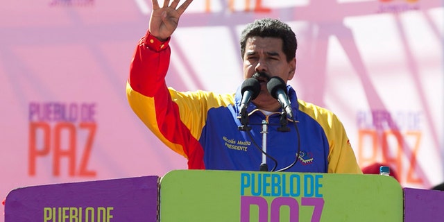 Venezuela's President Nicolas Maduro speaks during a rally on Bolivar Avenue in downtown Caracas, Venezuela, Saturday, Feb. 15, 2014. The signs read in Spanish "People of peace." Maduro said a police manhunt is underway for opposition leader Leopoldo Lopez, and denounced what he said is a "fascist" plot to oust him from power. (AP Photo/Alejandro Cegarra)
