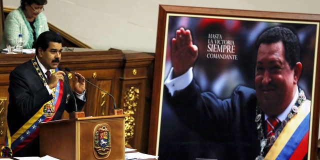 President Nicolas Maduro speaks next to a framed poster of the late Hugo Chavez before the National Assembly in Caracas, Venezuela, Jan. 15, 2014.