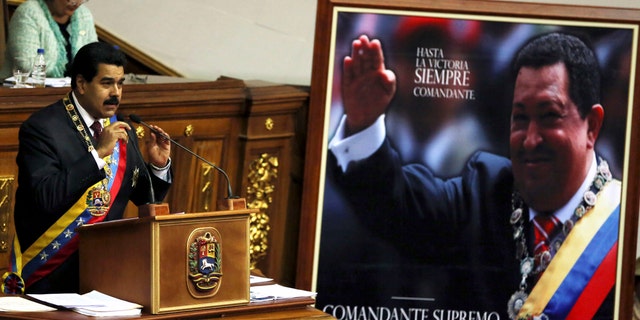 President Nicolas Maduro speaks next to a framed poster of the late Hugo Chavez before the National Assembly in Caracas, Venezuela, Jan. 15, 2014.