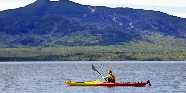 Kayaker paddles on Moosehead Lake at Lily Bay State Park, Beaver Cove, Maine.
