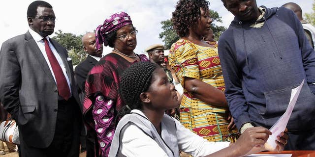 Background from left to right, Chief Justice Richard Banda, his wife, Malawi President Joyce Banda, and younger sister Anjimile Mtila-Oponyo, join a voting queue to cast their votes in the eastern district of Zomba, Malawi, Tuesday, May 20, 2014. Africa's second female president Joyce Banda is facing stiff challenges from a field of 12 candidates in Malawi's elections Tuesday. (AP Photo/Raphael Tenthani)