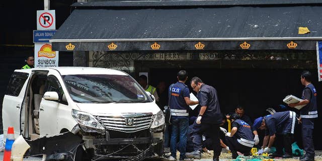 Malaysian forensic police officers investigate the scene where a grenade exploded outside a night club in Kuala Lumpur, Malaysia, Thursday, Oct. 9, 2014. Malaysian police say one person died and 13 others injured when a hand grenade blew up Thursday at the popular tourist belt in the country's largest city. (AP Photo) MALAYSIA OUT