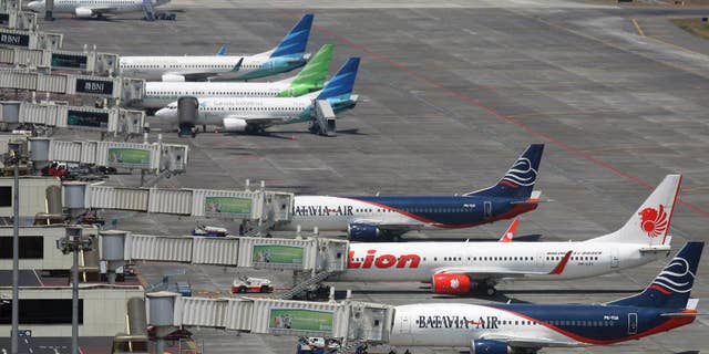 FILE - In this Sept. 25, 2012 file photo, budget airlines' passenger jets, Malaysia's AirAsia, top, Indonesia's Badavia Air, third from bottom, and Indonesia's Lion Air, second bottom, are parked on the tarmac with Indonesian planes of domestic airline Merpati Nusantara, second top, and the flagship carrier Garuda Indonesia at Juanda International Airport in Surabaya, East Java, Indonesia. Air travel in Asia is surging as the middle class gets bigger, discount airlines proliferate and business ties with the rest of the world deepen. (AP Photo/Trisnadi, File)