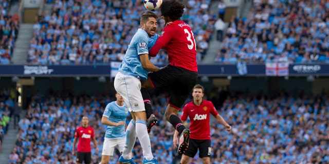 Manchester City's Aleksander Kolarov, centre left, jumps for the ball against Manchester United's Marouane Fellaini during their English Premier League soccer match at the Etihad Stadium, Manchester, England, Sunday Sept. 22, 2013. (AP Photo/Jon Super)
