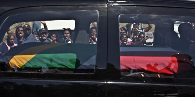 December 14, 2013: South African mourners wave and cheer as the hearse transporting the body of Former President Nelson Mandela passes through the town of Mthatha on its way to Qunu, South Africa. (AP Photo/Muhammed Muheisen)