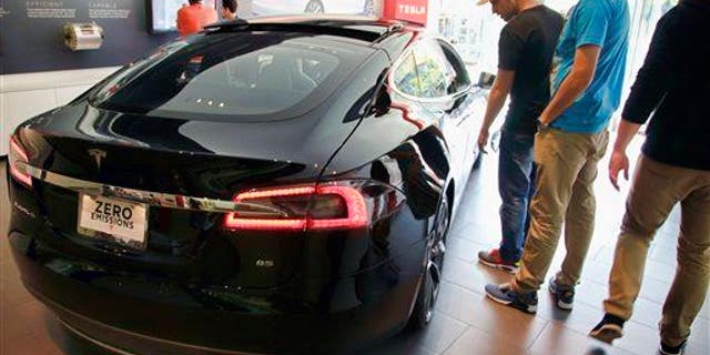 In this Saturday, Jan. 3, 2015 photo, people check out the Tesla model S at the Tesla showroom at the the Third Street Promenade in Santa Monica, Calif.
