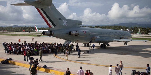 Hundreds of stranded tourists gather around a Mexican Air Force jet as they wait to be evacuated, at the air base in Pie de la Cuesta, near Acapulco, Mexico, Tuesday, Sept. 17, 2013. With roads blocked by landslides, rockslides, floods and collapsed bridges, Acapulco was cut off from road transport after Tropical Storm Manuel made landfall on Sunday. The airport as well, was flooded. Emergency flights began arriving in Acapulco to evacuate at least 40,000 mainly Mexican tourists stranded in the resort city. (AP Photo/Eduardo Verdugo)