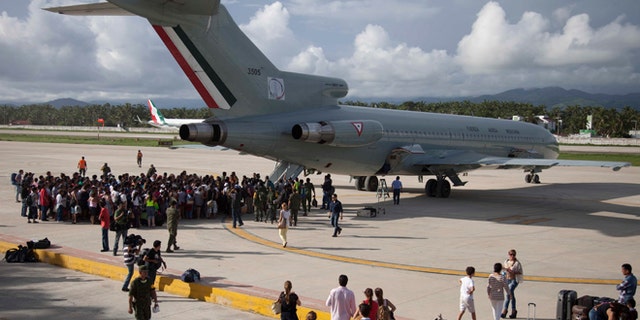 Hundreds of stranded tourists gather around a Mexican Air Force jet as they wait to be evacuated, at the air base in Pie de la Cuesta, near Acapulco, Mexico, Tuesday, Sept. 17, 2013. With roads blocked by landslides, rockslides, floods and collapsed bridges, Acapulco was cut off from road transport after Tropical Storm Manuel made landfall on Sunday. The airport as well, was flooded. Emergency flights began arriving in Acapulco to evacuate at least 40,000 mainly Mexican tourists stranded in the resort city. (AP Photo/Eduardo Verdugo)