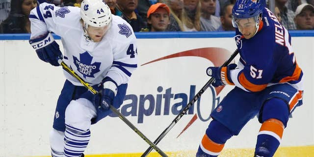 Toronto Maple Leafs defenseman Morgan Rielly (44) and New York Islanders center Frans Nielsen (51), of Denmark, compete for control of the puck during the second period of an NHL hockey game in Uniondale, N.Y., Tuesday, Oct. 21, 2014. (AP Photo/Kathy Willens)