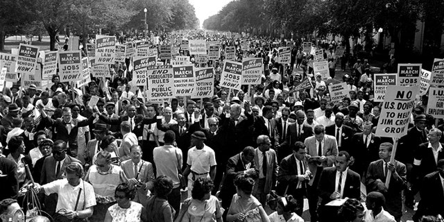 In this Aug. 28, 1963, file photo Dr. Martin Luther King Jr., center left with arms raised, marches along Constitution Avenue with other civil rights protesters carrying placards, from the Washington Monument to the Lincoln Memorial during the March on Washington. (AP Photo, File)