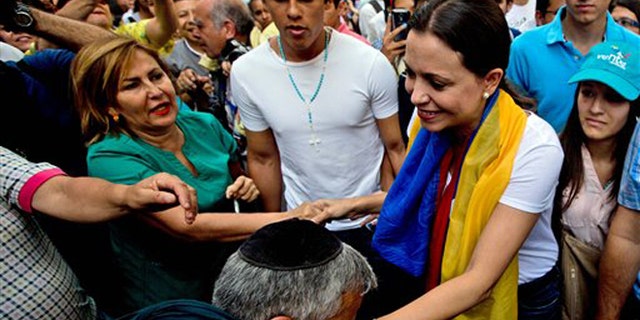 A man kisses the hand of leading opposition politician Maria Corina Machado as she arrives for a rally in Caracas, Venezuela, Wednesday, March 26, 2014. The head of Venezuela's congress, Diosdado Cabello, said Monday that Machado, who was stripped of her parliament seat, violated the constitution by addressing the Organization of American States last week at the invitation of Panama, which ceded its seat at the Washington-based group group so she could provide regional diplomats with a firsthand account of the unrest. (AP Photo/Fernando Llano)