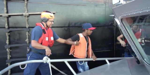 In this Wednesday, May 4, 2016 image taken from video, an unidentified mariner, center, is helped onto a U.S. Coast Guard cutter after being rescued at sea more than 2,000 miles southeast of Hawaii. The Colombian man survived a two-month ordeal in the Pacific by eating fish and seagulls, the U.S. Coast Guard said. (U.S. Coast Guard via AP)