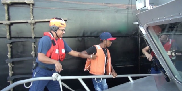 In this Wednesday, May 4, 2016 image taken from video, an unidentified mariner, center, is helped onto a U.S. Coast Guard cutter after being rescued at sea more than 2,000 miles southeast of Hawaii. The Colombian man survived a two-month ordeal in the Pacific by eating fish and seagulls, the U.S. Coast Guard said. (U.S. Coast Guard via AP)
