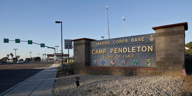 Vehicles file through the main gate of Camp Pendleton Marine Base on Wednesday, Nov. 13, 2013, at Camp Pendleton, Calif. Four Marines were reported killed today in an accident while clearing an unexploded ordnance. (AP Photo/Lenny Ignelzi)