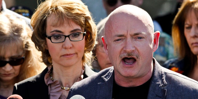 March 6, 2013: Former Rep. Gabrielle Giffords listens to her husband, Mark Kelly, during a return to the supermarket where she was wounded in a rampage two years ago in Tucson, Ariz.