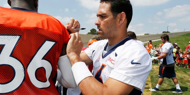 Denver Broncos quarterback Mark Sanchez, right, jokes around by signing the jersey of cornerback Kayvon Webster as they work a rope line to signs autographs for fans after taking part in the team's NFL football training camp Friday, July 29, 2016 in Englewood, Colo. (AP Photo/David Zalubowski)
