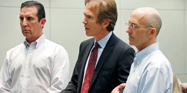 In this May 22, 2014 photograph, Mark Mayfield, right, a member of the board of the Central Mississippi Tea Party, and attorney John Reeves, left, listen as Mayfield's attorney Merrida Coxwell, center, responds to questions from city Judge Dale Danks in Madison, Miss., city court, during an initial court appearance.