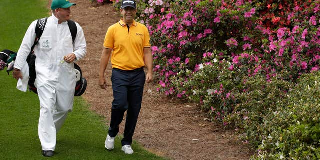 April 6, 2015: Erik Compton walks with his caddie down the sixth fairway during a practice round for the Masters golf tournament.