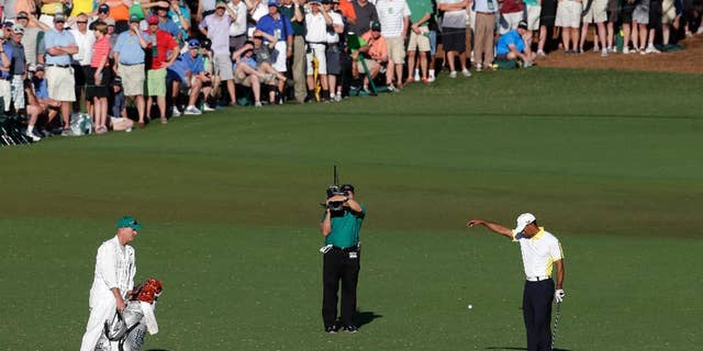 FILE - In this April 12, 2013 file photo, Tiger Woods takes a drop on the 15th hole after his ball went into the water during the second round of the Masters golf tournament in Augusta, Ga. Players as well as the rule officials come from all around the world to the Masters, making the official rulings as discussed as the score. (AP Photo/Charlie Riedel, File)
