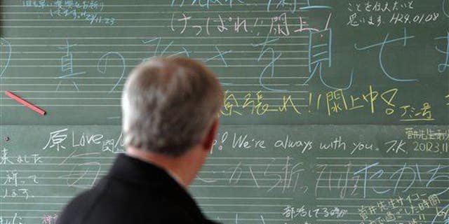 Prime Minister Stephen Harper looks at a chalk board filled with well wishes at the Yuriage Junior High School as he visits the coastal region of Japan, near Sendai, on Monday, March 26, 2012.
