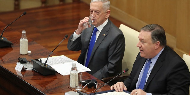U.S. Defense Secretary James Mattis, left, drinks water as U.S. Secretary of State Mike Pompeo, makes his statement after meeting in New Delhi, India, Thursday with Indian officials.