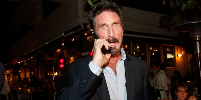 Anti-virus software founder John McAfee talks on his mobile phone as he walks on Ocean Drive in the South Beach area of Miami Beach, Fla., on his way to dinner Wednesday, Dec 12, 2012. McAfee arrived in the U.S. on Wednesday night after being deported from Guatemala, where he had sought refuge to evade police questioning in the killing of a man in neighboring Belize. (AP Photo/Alan Diaz)