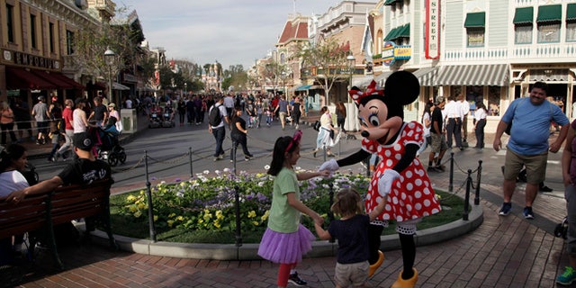 Minnie Mouse dances with visitors at Disneyland, Thursday, Jan. 22, 2015, in Anaheim, Calif. A major measles outbreak traced to Disneyland has brought criticism down on the small but vocal movement among parents to opt out of vaccinations for their children. (AP Photo/Jae C. Hong)
