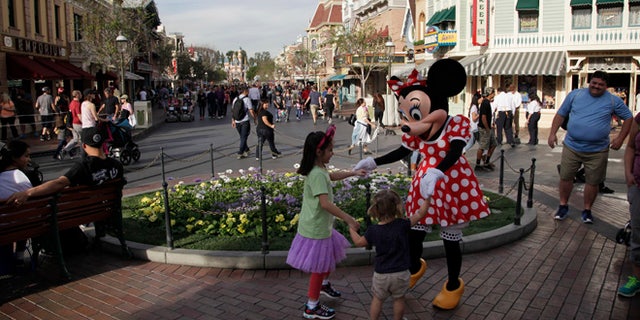 Minnie Mouse dances with visitors at Disneyland, Thursday, Jan. 22, 2015, in Anaheim, Calif. A major measles outbreak traced to Disneyland has brought criticism down on the small but vocal movement among parents to opt out of vaccinations for their children. (AP Photo/Jae C. Hong)