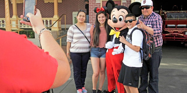 Visitors pose with Mickey Mouse at Disneyland in Anaheim, Calif.