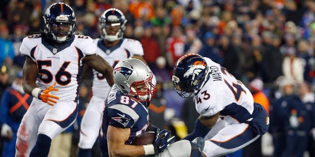 FILE - In this Nov. 2, 2014, file photo, New England Patriots tight end Rob Gronkowski (87) lands between Denver Broncos middle linebacker Nate Irving (56) and strong safety T.J. Ward (43) after catching a pass in the fourth quarter of an NFL football game in Foxborough, Mass. Gronkowski's leaping, full-extension, one-handed, lefty grab of a pass from Tom Brady against the Broncos made perfectly clear that the man known as "Gronk" is back among the NFL's elite after a series of operations to his left forearm, his right knee and his back. (AP Photo/Elise Amendola, File)