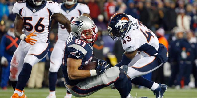 FILE - In this Nov. 2, 2014, file photo, New England Patriots tight end Rob Gronkowski (87) lands between Denver Broncos middle linebacker Nate Irving (56) and strong safety T.J. Ward (43) after catching a pass in the fourth quarter of an NFL football game in Foxborough, Mass. Gronkowski's leaping, full-extension, one-handed, lefty grab of a pass from Tom Brady against the Broncos made perfectly clear that the man known as "Gronk" is back among the NFL's elite after a series of operations to his left forearm, his right knee and his back. (AP Photo/Elise Amendola, File)
