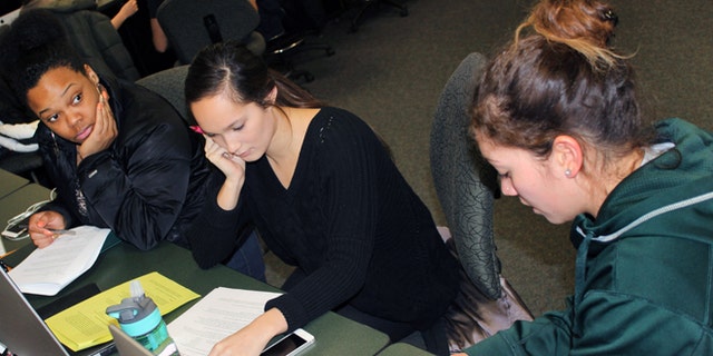 In this March 1, 2015 photo released by Joe Grimm, Michigan State University students Tiara Jones, from left, Madeline Carino and Lia Kamana work on a new book â100 Questions and Answers About Veteransâ in East Lansing, Mich. The new book, researched and written by a Michigan State journalism class with assistance from former servicemen and women, is aimed at clearing up myths and misunderstandings held by some civilians.  (AP Photo/Joe Grimm)