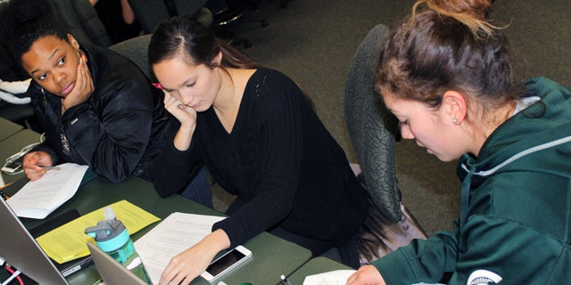 In this March 1, 2015 photo released by Joe Grimm, Michigan State University students Tiara Jones, from left, Madeline Carino and Lia Kamana work on a new book â100 Questions and Answers About Veteransâ in East Lansing, Mich. The new book, researched and written by a Michigan State journalism class with assistance from former servicemen and women, is aimed at clearing up myths and misunderstandings held by some civilians. (AP Photo/Joe Grimm)