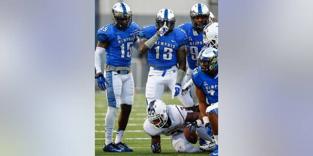 Memphis defender Tank Jakes, center,  celebrates a tackle of UConn’s Ron Johnson, bottom. during first half action of the NCAA college football game Saturday, Nov. 29, 2014, in Memphis, Tenn.  Memphis' Fritz Etiene (15) and Rocly Hunter (91) flank Jakes.(AP Photo/The Commercial Appeal, Mark Weber)