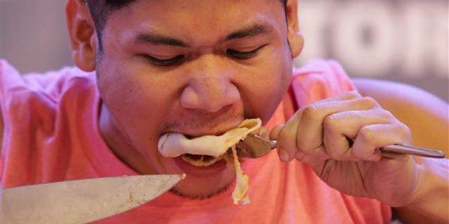 Filipino Rix Francisco eats pizza as he attempts to break the world record for the fastest time to eat a 12-inch pizza in Makati in the Philippines on April 12, 2015.