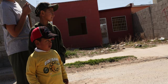 JUAREZ, MEXICO - MARCH 21: A woman and her sons stand in front of an abandoned home on March 21, 2010 in Juarez, Mexico. The border city of Juarez has suffered from the duel effects of the recession in America and the surge in drug violence. An estimated 100,000 jobs having been lost since the recession and some 10,000 businesses have been closed in the past 18 months. City officials also say that thousands of homes have been abandoned as residents leave for El Paso or safer cities in Mexico. Juarez has been racked by violent drug related crime recently and has quickly become one of the most dangerous cities in the world to live. As drug cartels have been fighting over ever lucrative drug corridors along the United States border, the murder rate in Juarez has risen to 173 slayings for every 100,000 residents. President Felipe Calderon in 2009 disbanded the corrupt local police force and sent 10,000 soldiers to Juarez, but the violence has raged on. With a population of 1.3 million in Juarez, 2,600 died in drug-related violence last year and 500 so far this year, including two Americans who worked for the U.S. Consulate last weekend as they returned from a children's party. (Photo by Spencer Platt/Getty Images)